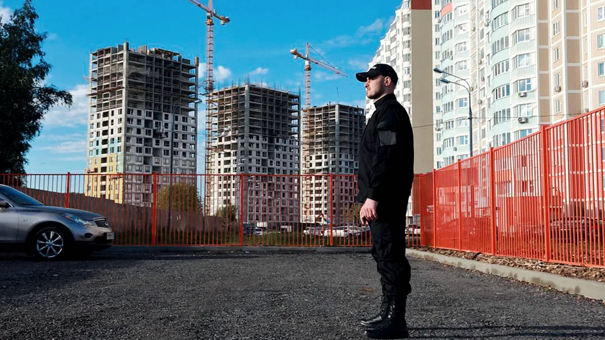 Охранник на посту у ограждения строительной площадки